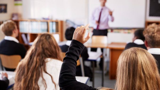 A pupil raising their hand in a classroom