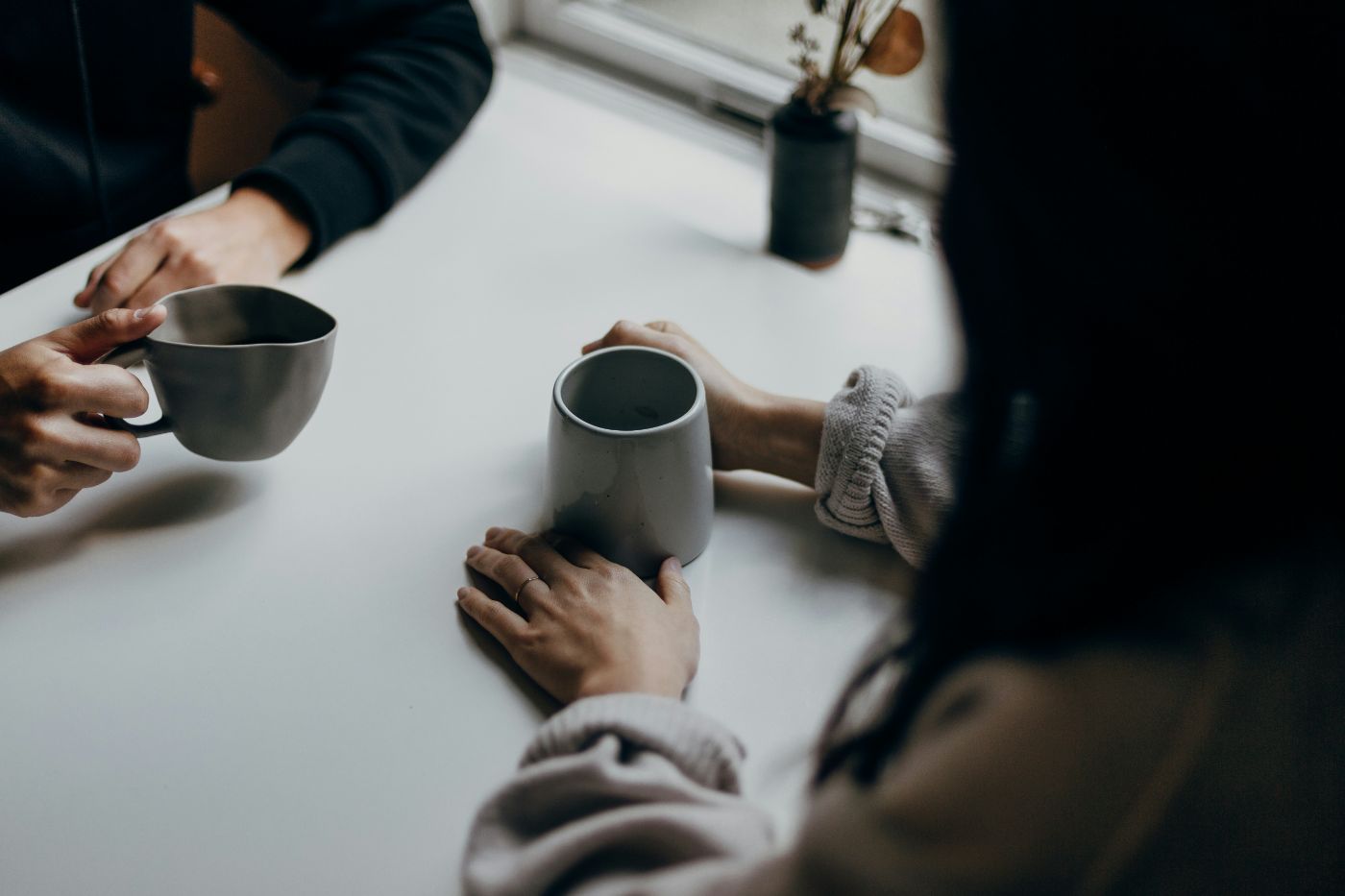Two people talking over mugs of tea at a table