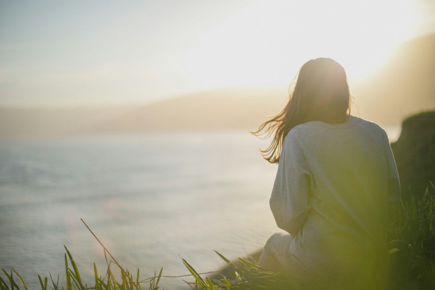 A woman sitting quietly by the sea at sunset